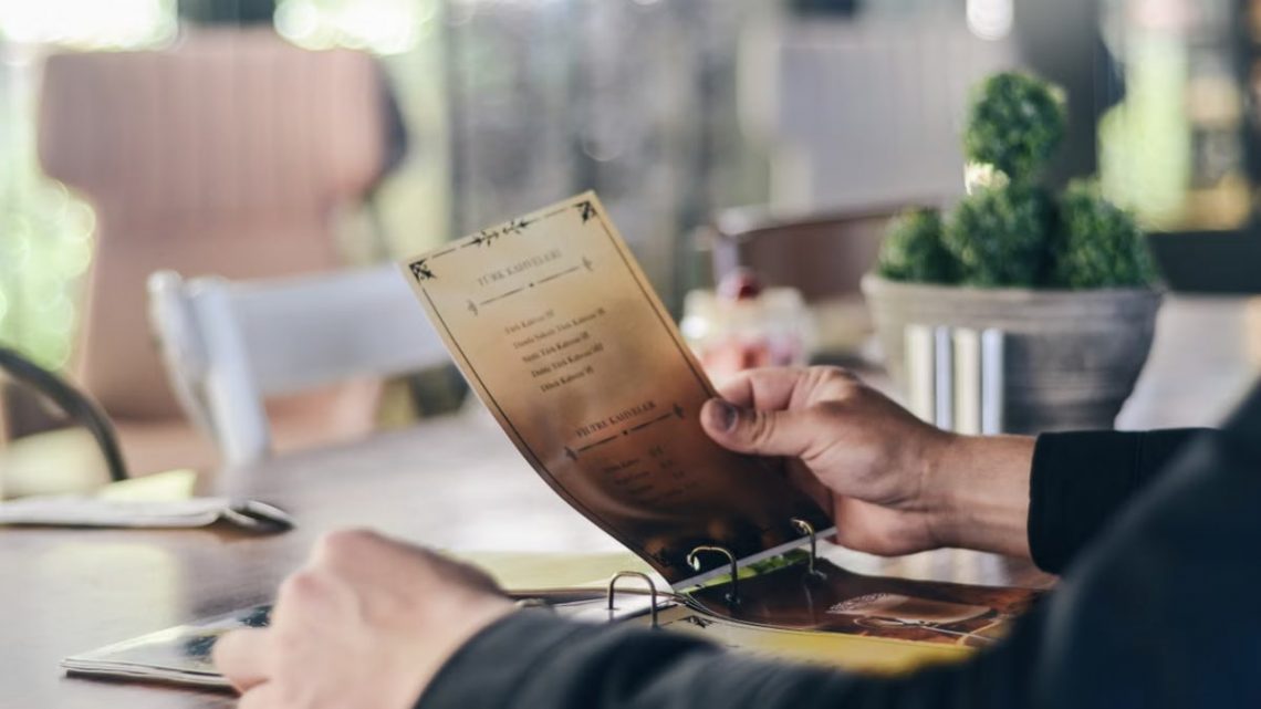 A person reading a menu in a contemporary restaurant, highlighting dining culture.