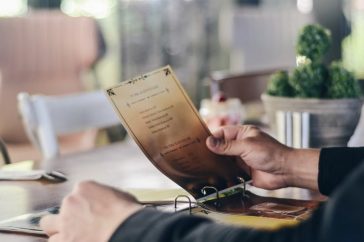 A person reading a menu in a contemporary restaurant, highlighting dining culture.