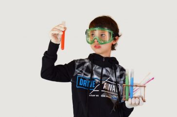 Young male scientist in protective glasses and sterile gloves with colorful liquids in transparent tubes