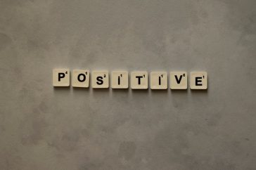 Scrabble tiles spelling 'Positive' on a textured surface, conveying optimism.
